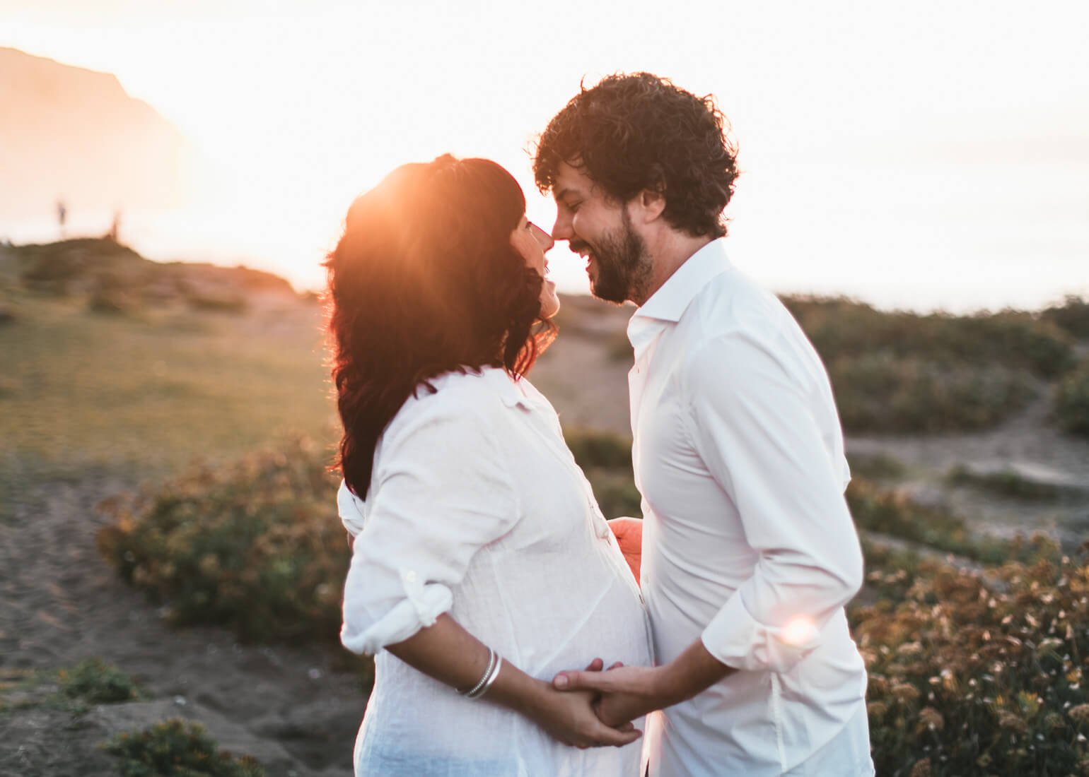 Embarazada bailando con su pareja al atardecer en la playa Bizkaia